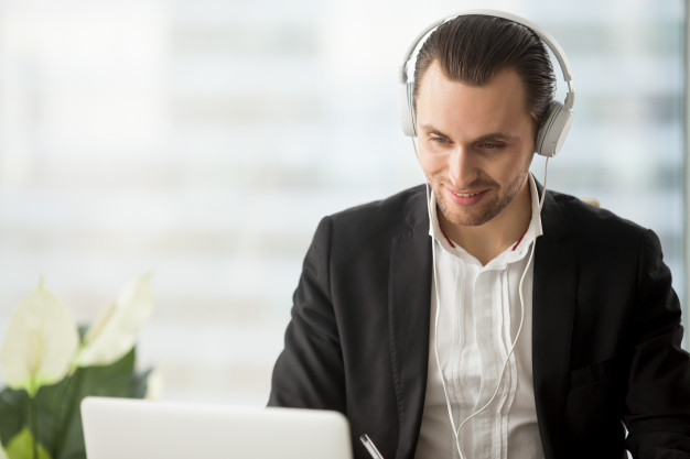 smiling-businessman-headphones-looking-laptop-screen_1163-5436